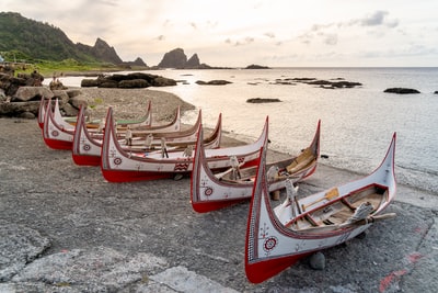 Red and white wooden boats in gray at the beach during the day
